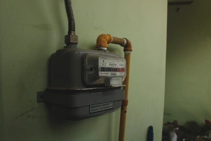 A gas meter mounted on a pale green wall.